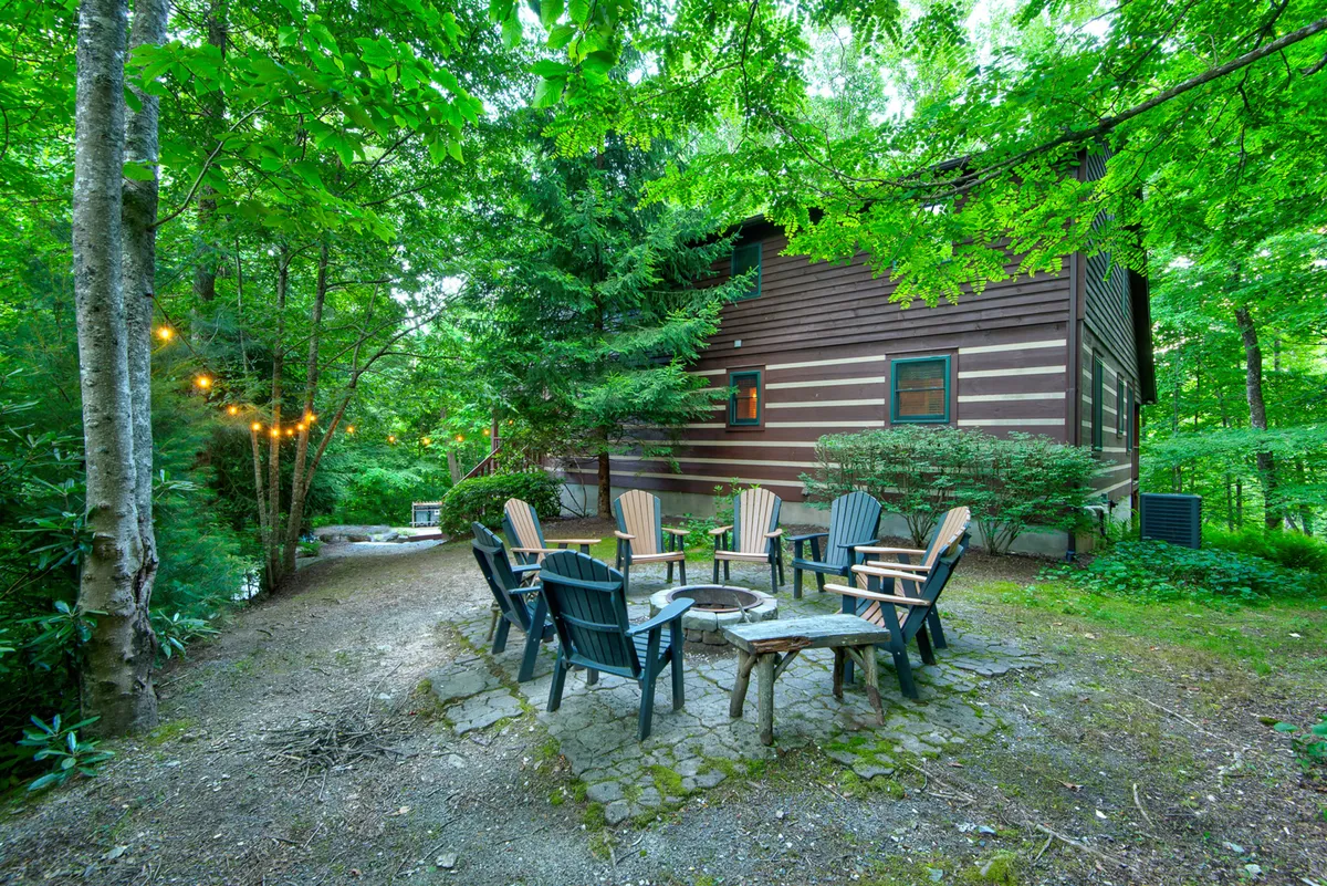 This image features a fire pit ringed by Adirondack chairs, nestled among lush greenery with the cabin exterior in the background. The scene invites group campfire storytelling, stargazing, and social gatherings—classic ingredients for multi-generational family fun after a day of adventure.